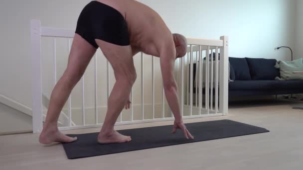 Un homme d'âge moyen fait ses exercices quotidiens sur un tapis de yoga à la maison.  - Séquence, vidéo