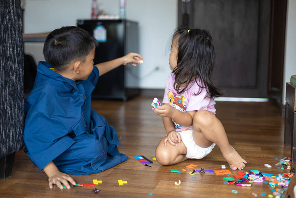 Azji siostra i brat grać razem w przytulnym pokoju drewniany dom podłogi dzieci z zabawką - Zdjęcie, obraz