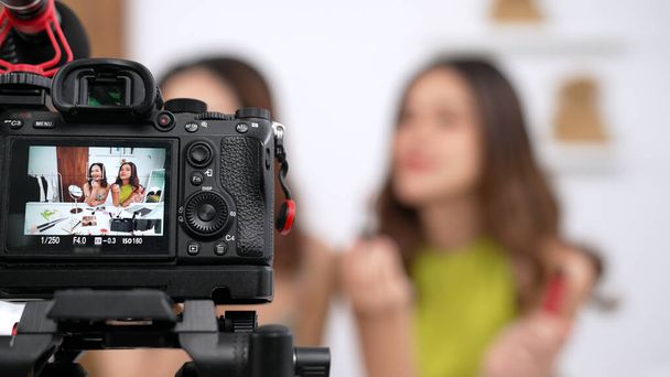 Zwei Influencer-Partner drehen Live-Streaming-Videos in sozialen Medien oder bloggen. Glückliches junges Mädchen mit lebhafter Kosmetik-Studiobeleuchtung für Marketing-Aufnahmen, die online übertragen werden. - Foto, Bild