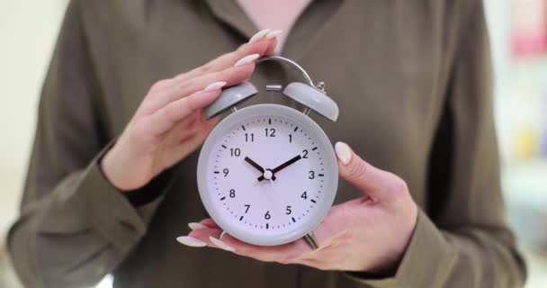 Liikenainen pitää herätyskelloa muistuttamassa aikarajasta. Nainen ilmentää tietoisuutta ja vastuuta, jotka liittyvät ratkaisevan määräajan noudattamiseen työssä - Materiaali, video