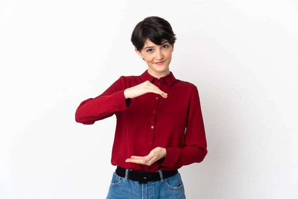 Mujer con el pelo corto aislado sobre fondo blanco sosteniendo copyspace imaginario en la palma de la mano para insertar un anuncio - Foto, imagen