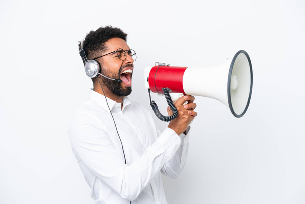 Telemarketer Brazilian man working with a headset isolated on white background shouting through a megaphone - Foto, Imagem