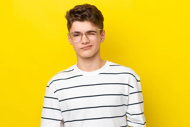 Teenager Russian man isolated on yellow background With glasses and happy expression - Photo, Image