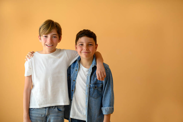 Porträt zweier Kinder, Freunde, die einander halten und auf dem Hintergrund mit Kopierraum lächeln - Foto, Bild