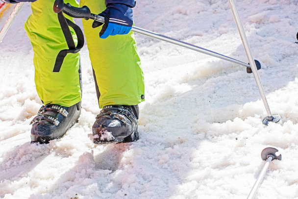Kayakçı karlı bir yamaçta kayak botları giyer. Aileyle aktif tatil - Fotoğraf, Görsel