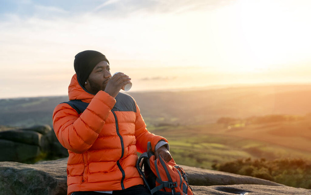 glücklicher gutaussehender Tourist mit Rucksack beim Wandern und bei Sonnenuntergang in England die Berglandschaft genießen. Ein Ausflug in die Berge mit Rucksack. Wandern und neue Orte erkunden - Foto, Bild