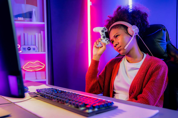 Afrikkalainen amerikkalainen tyttö serpentiini pettynyt pelaa verkossa taistelevat Esport taitava joukkue yllään kuulokkeet neon huoneessa. Puhuminen muut pelaajat höyläys strategioita voittaa kilpailijoita. Maustevalmistaja. - Valokuva, kuva