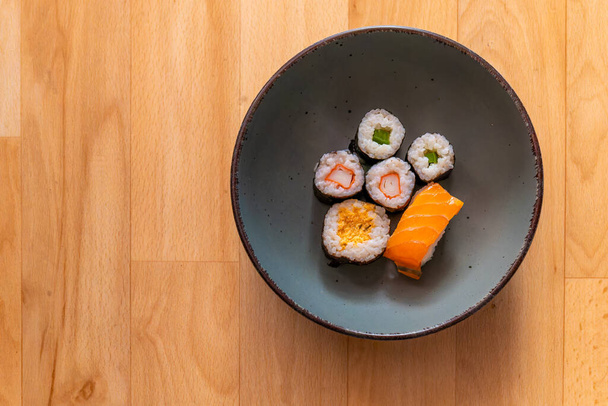 un tazón de sushi surtido se sienta en una mesa de madera - Foto, imagen