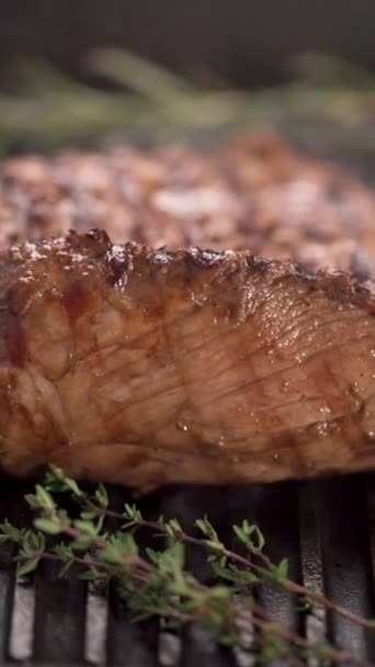 Close-up of beef steak grilling with herbs, vertical video. Copy space - Footage, Video