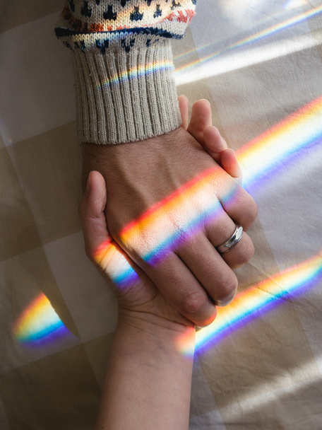 Hand in Hand mit Regenbogen, der sentimentale Verbundenheit symbolisiert - Foto, Bild