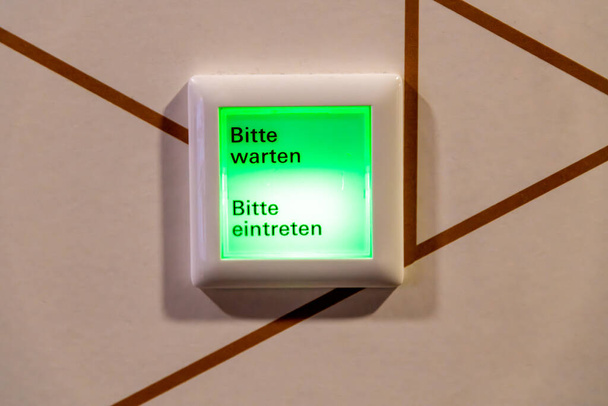 Bautzen, Saxe - Allemagne - 04-10-2021 : Un panneau vert avec 'Bitte warten' et 'Bitte eintreten', indiquant les instructions d'attente et d'entrée - Photo, image