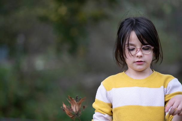 Retrato de una niña pequeña en un suéter amarillo y gafas. - Foto, imagen
