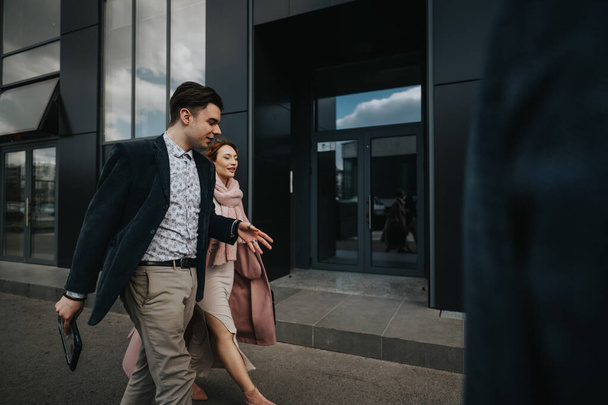 Молодой профессиональный предприниматель покидает офисный комплекс с уверенным шагом рядом с женщиной-партнером. - Фото, изображение