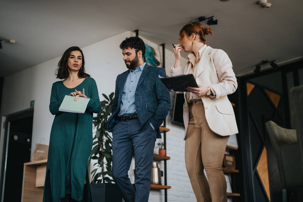 Tres personas creativas colaboran y comparten ideas durante una reunión de negocios en un entorno de oficina contemporáneo - Foto, imagen