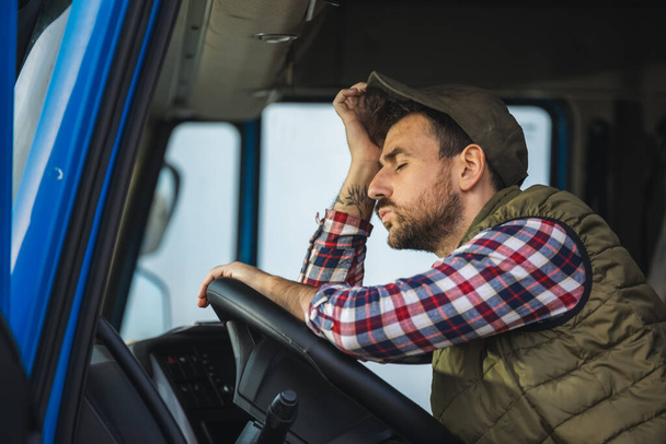 Уставший водитель грузовика делает перерыв в вождении и отдыхает в грузовике - Фото, изображение