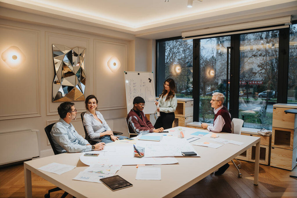 Een multigenerationele groep professionals neemt deel aan een levendige brainstormsessie in een goed verlichte kantoorvergaderruimte. Ze zijn gericht op de presentatie terwijl ze ideeën en concepten delen.. - Foto, afbeelding