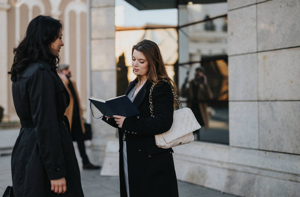 Two young businesswomen engaging in conversation outdoors in the city. - Photo, Image