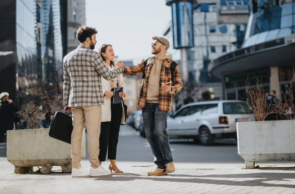Three young business professionals discuss strategies and analyze trends while standing outdoors in a city setting. - Photo, Image