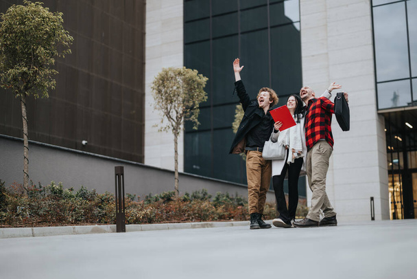 Three business professionals ecstatic with success, celebrating with high fives outside a contemporary office. - Photo, Image