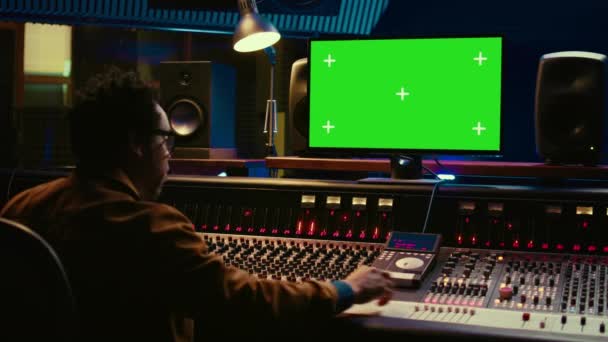 Africký zvukový inženýr používá zelenou obrazovku na PC v profesionálním nahrávacím studiu, pracuje s mixováním konzole a kroucení knoflíky pro editaci stop. Hudební producent vytváří melodie. Fotoaparát B. - Záběry, video