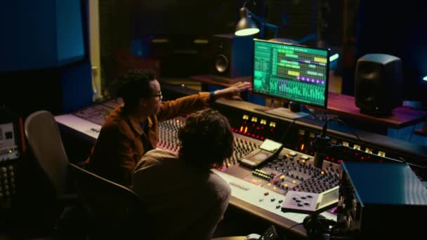 Diverses personnes traitent et mixent les sons sur la console audio, ajoutant des effets sonores et travaillant sur la création de nouvelles pistes. Artiste et technicien produisant une chanson à succès, logiciel daw. Caméra B. - Séquence, vidéo