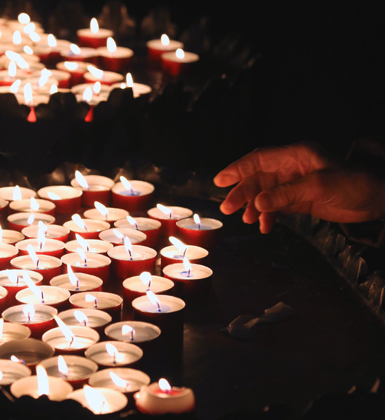 mão de uma mulher idosa acende uma vela para rezar
 - Foto, Imagem