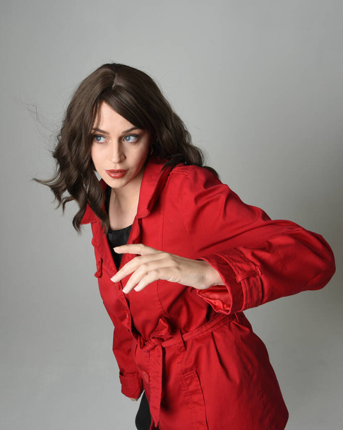 głowa i ramiona zbliżyć portret pięknej brunetki model kobiety, w czerwonym płaszczu Trench. izolowane na białym tle studio, perspektywa wysokiego kąta - Zdjęcie, obraz