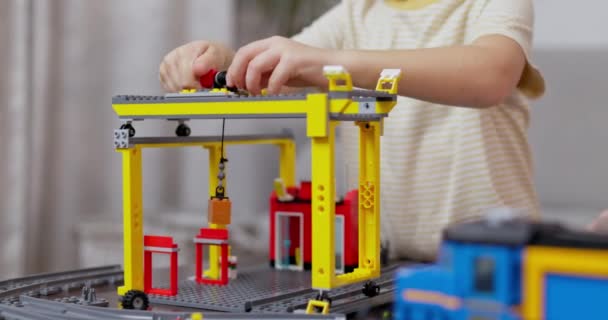 Niño enfocado montando una grúa de construcción modelo de un conjunto de bloques de colores, que representa un sitio de trabajo en miniatura. Imágenes de alta calidad 4k - Metraje, vídeo
