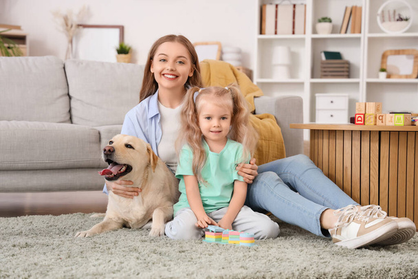 Маленькая девочка с матерью и собакой-лабрадором дома - Фото, изображение
