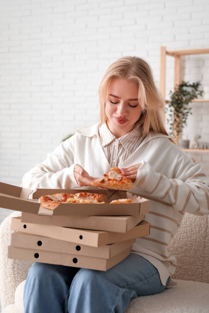 Молода жінка тримає коробки зі смачною піцою вдома - Фото, зображення