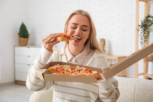Nuori nainen syö herkullista pizzaa kotona - Valokuva, kuva