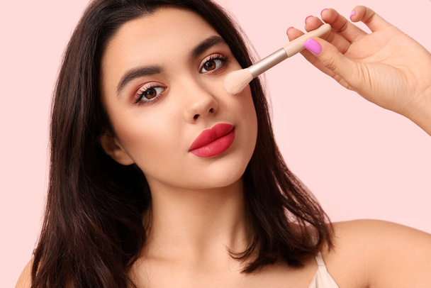 Beautiful young woman with stylish makeup and brush on pink background - Φωτογραφία, εικόνα