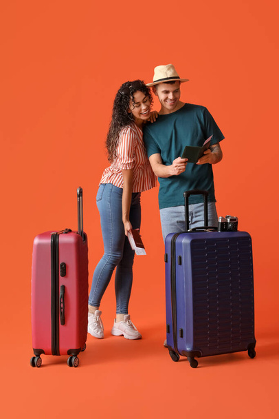 Couple of tourists with suitcases and passports on orange background - Foto, Imagem