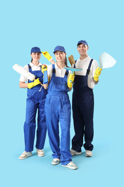 Werknemers van schoonmaakdiensten met benodigdheden op blauwe achtergrond - Foto, afbeelding