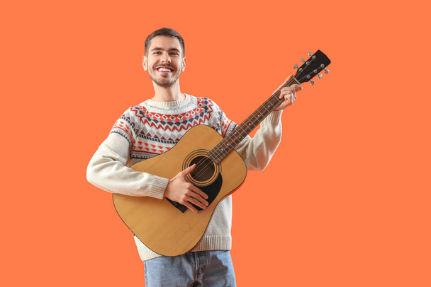 csinos, fiatal férfi a gitár a narancssárga háttér - Fotó, kép