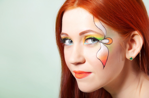 Close-up portrait of beautiful red-haired girl with flower painted on his face - Photo, Image