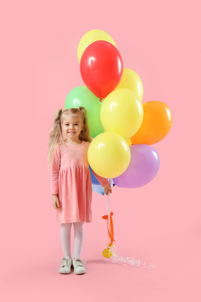 ピンクの背景にカラフルな風船を持つ幸せな笑顔の少女 - 写真・画像
