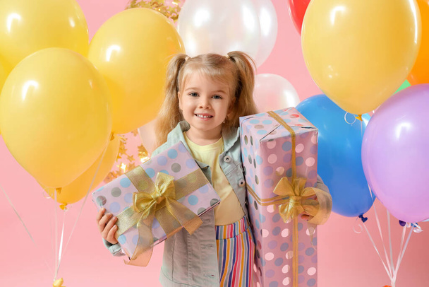 Happy little girl with colorful balloons and gift boxes on pink background - Photo, Image