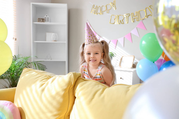 Menina bonito em chapéu de festa com balões e decorações para o aniversário em casa - Foto, Imagem