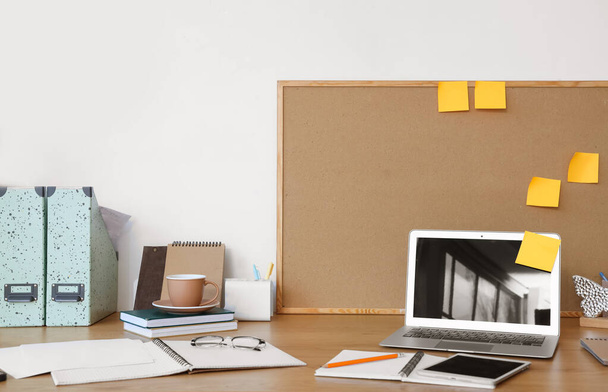 Arbeitsplatz mit Laptop, Notebooks und Board mit Haftnotizen im Büro - Foto, Bild