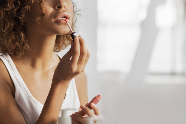 Girl applying lip gloss, reflecting in mirror in bathroom - Φωτογραφία, εικόνα