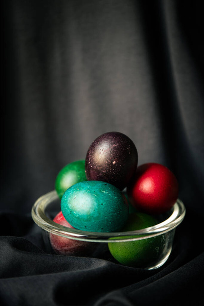 Huevos coloridos de Pascua en una tela oscura. - Foto, imagen
