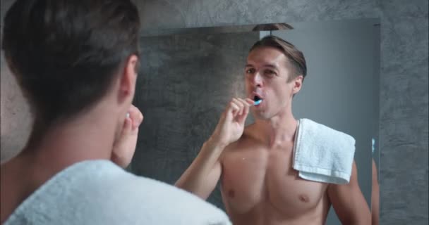 Man bathroom, bare torso, white towel on shoulder, suddenly experiences tooth pain while brushing, health issues. unexpected nature health issues, underlining importance awareness care health issues - Footage, Video