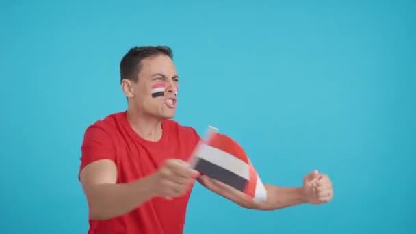 Stüdyoda, Mısır 'a tezahürat yapan bir adamın krom renkli videosu var. Çığlık atıyor ve elinde ulusal bir bayrak sallıyor. Boş bir şekilde fotokopi odasına bakıyor. - Video, Çekim