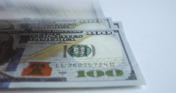 Sto amerykańskich banknotów leży na białym stole. Zbliżenie pokazuje szczegóły banknotów: portrety, ozdoby, znaki wodne. Zardzewiałe rachunki wypełniają powietrze poczuciem bogactwa i sukcesu - Materiał filmowy, wideo