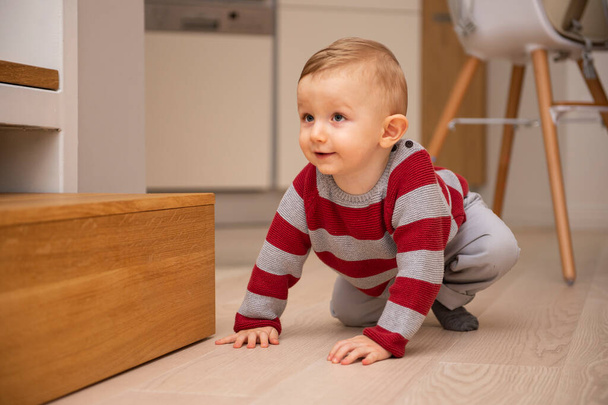 Ein süßer kleiner Junge krabbelt auf dem Holzboden in der Wohnung. - Foto, Bild
