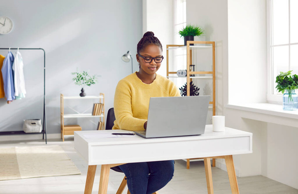 Portrait of a young african american brunette business woman working with laptop computer at home or at ofiice and typing. Accountant freelancer considering new projects, analyzing company. - Foto, Imagem