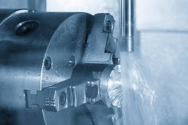 4-osiowa frezarka CNC tnąca część turbosprężarki metodą cieczy chłodzącej. Zaawansowany technologicznie proces produkcji części samochodowych przez wieloosiowe centrum obróbcze. - Zdjęcie, obraz