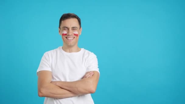Βίντεο σε στούντιο με chroma ενός άνδρα στέκεται με πολωνική σημαία ζωγραφισμένα στο πρόσωπο χαμογελώντας με τα χέρια σταυρωμένα - Πλάνα, βίντεο