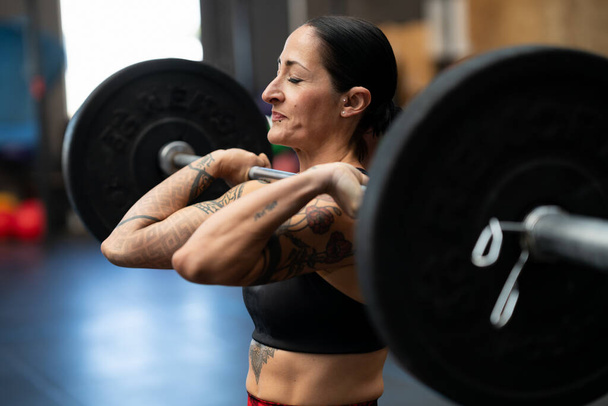 Donna forte sportiva che fa uno sforzo per sollevare pesi in una palestra di cross training - Foto, immagini